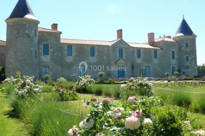 Un couple marche dans le jardin d'un château ancien entouré de verdure par une journée ensoleillée.