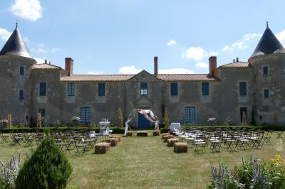 Un couple marche dans le jardin d'un château ancien entouré de verdure par une journée ensoleillée.
