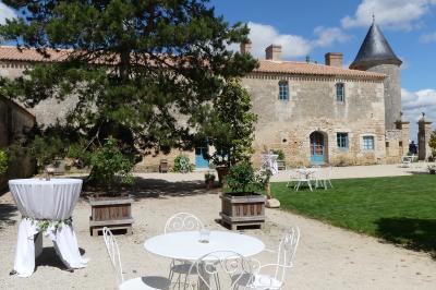 Un couple marche dans le jardin d'un château ancien entouré de verdure par une journée ensoleillée.