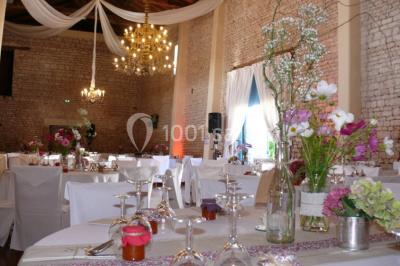 Un couple marche dans le jardin d'un château ancien entouré de verdure par une journée ensoleillée.