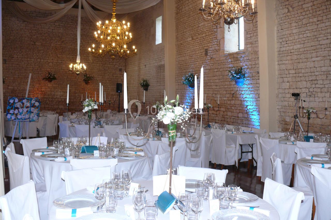 Salle de réception décorée pour un mariage, avec tables dressées, chandeliers et éclairage chaleureux.