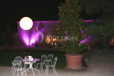 Un couple marche dans le jardin d'un château ancien entouré de verdure par une journée ensoleillée.