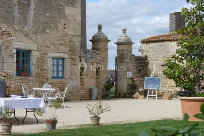 Un couple marche dans le jardin d'un château ancien entouré de verdure par une journée ensoleillée.
