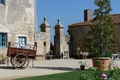 Un couple marche dans le jardin d'un château ancien entouré de verdure par une journée ensoleillée.