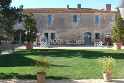 Un couple marche dans le jardin d'un château ancien entouré de verdure par une journée ensoleillée.