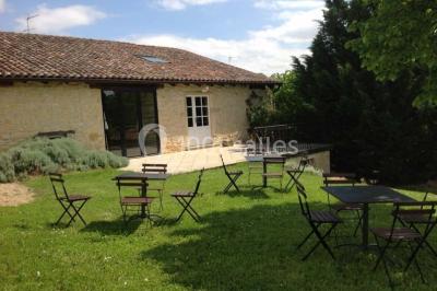 Salle de réunion avec tables disposées en U, chaises rouges, paperboards et décorations végétales.