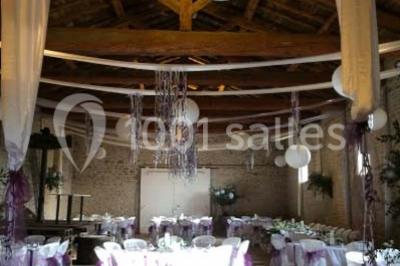 Salle de réunion avec tables disposées en U, chaises rouges, paperboards et décorations végétales.
