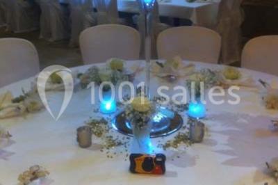 Salle de réunion avec tables disposées en U, chaises rouges, paperboards et décorations végétales.