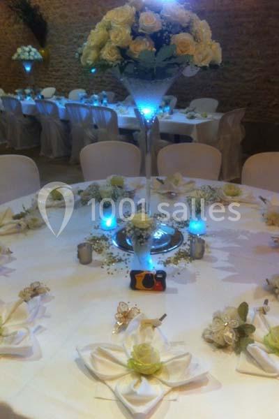 Table décorée pour un mariage avec nappes blanches, fleurs, bougies et un centre de table illuminé.