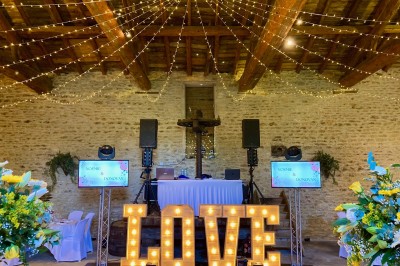 Table en bois avec des objets décoratifs, posée contre un mur en pierre dans une pièce lumineuse au sol en terre cuite.
