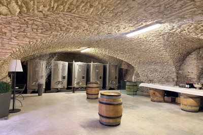 Table en bois avec des objets décoratifs, posée contre un mur en pierre dans une pièce lumineuse au sol en terre cuite.