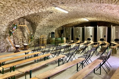 Table en bois avec des objets décoratifs, posée contre un mur en pierre dans une pièce lumineuse au sol en terre cuite.