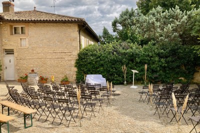 Table en bois avec des objets décoratifs, posée contre un mur en pierre dans une pièce lumineuse au sol en terre cuite.