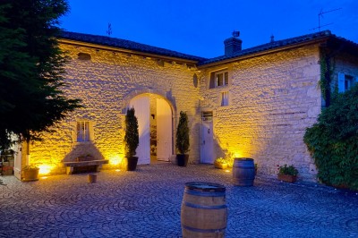 Table en bois avec des objets décoratifs, posée contre un mur en pierre dans une pièce lumineuse au sol en terre cuite.