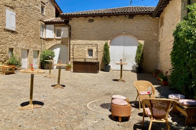 Table en bois avec des objets décoratifs, posée contre un mur en pierre dans une pièce lumineuse au sol en terre cuite.