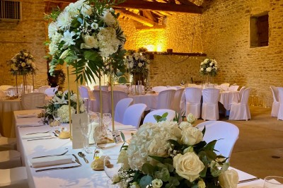 Table en bois avec des objets décoratifs, posée contre un mur en pierre dans une pièce lumineuse au sol en terre cuite.
