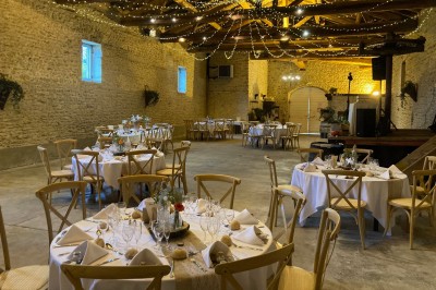 Table en bois avec des objets décoratifs, posée contre un mur en pierre dans une pièce lumineuse au sol en terre cuite.