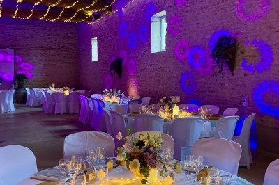 Table en bois avec des objets décoratifs, posée contre un mur en pierre dans une pièce lumineuse au sol en terre cuite.