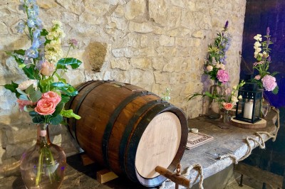 Table en bois avec des objets décoratifs, posée contre un mur en pierre dans une pièce lumineuse au sol en terre cuite.