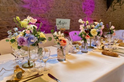 Table en bois avec des objets décoratifs, posée contre un mur en pierre dans une pièce lumineuse au sol en terre cuite.