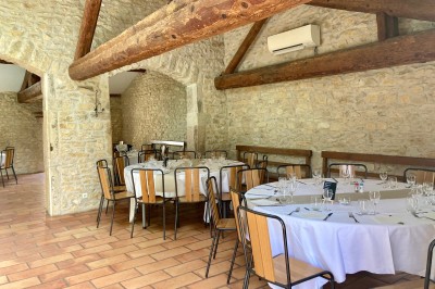Table en bois avec des objets décoratifs, posée contre un mur en pierre dans une pièce lumineuse au sol en terre cuite.