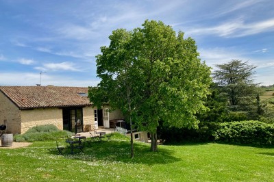 Table en bois avec des objets décoratifs, posée contre un mur en pierre dans une pièce lumineuse au sol en terre cuite.