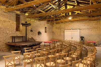 Table en bois avec des objets décoratifs, posée contre un mur en pierre dans une pièce lumineuse au sol en terre cuite.