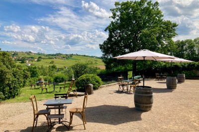 Table en bois avec des objets décoratifs, posée contre un mur en pierre dans une pièce lumineuse au sol en terre cuite.