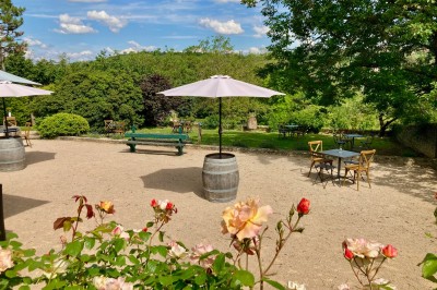 Table en bois avec des objets décoratifs, posée contre un mur en pierre dans une pièce lumineuse au sol en terre cuite.