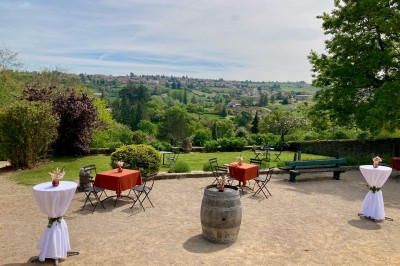 Table en bois avec des objets décoratifs, posée contre un mur en pierre dans une pièce lumineuse au sol en terre cuite.