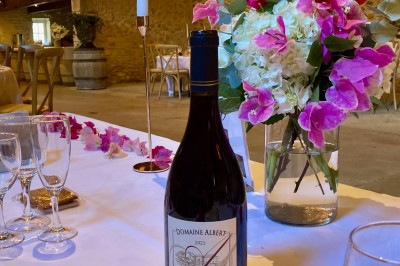 Table en bois avec des objets décoratifs, posée contre un mur en pierre dans une pièce lumineuse au sol en terre cuite.
