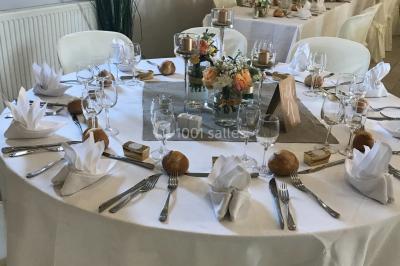 Petit pont en fer forgé traversant un cours d'eau bordé d'arbres, près d'une maison en pierre avec toit en ardoise.