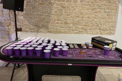 Petit pont en fer forgé traversant un cours d'eau bordé d'arbres, près d'une maison en pierre avec toit en ardoise.