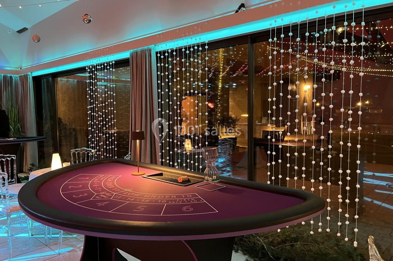 Table de jeu de casino violette dans une salle décorée avec des lumières et des guirlandes, ambiance festive.
