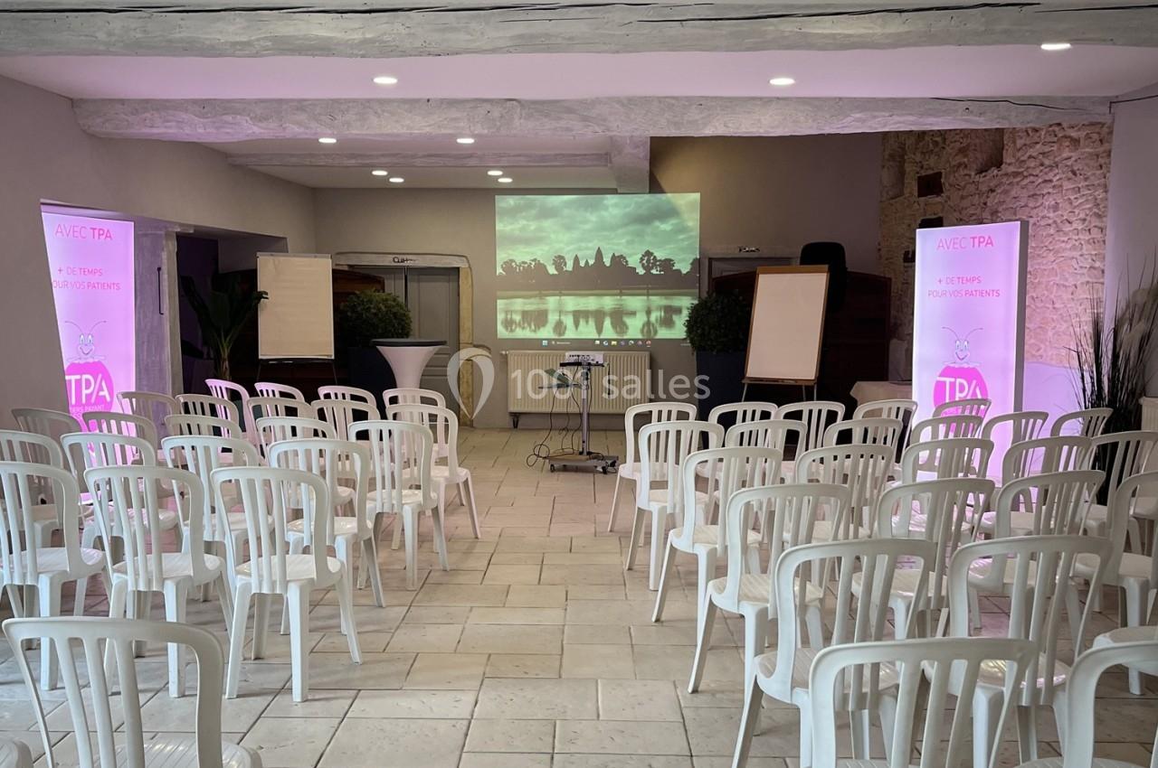 Salle de conférence avec chaises blanches alignées, projecteur affichant une image de paysage sur un écran.