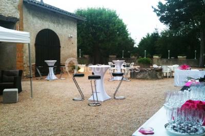 Petit pont en fer forgé traversant un cours d'eau bordé d'arbres, près d'une maison en pierre avec toit en ardoise.
