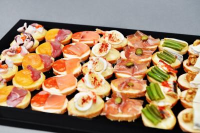 Petit pont en fer forgé traversant un cours d'eau bordé d'arbres, près d'une maison en pierre avec toit en ardoise.