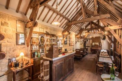 Chambre d'hôtel lumineuse avec lit double, coussins rouges, bureau, télévision et fenêtre donnant sur un balcon fleuri.
