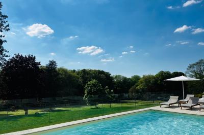 Chambre d'hôtel lumineuse avec lit double, coussins rouges, bureau, télévision et fenêtre donnant sur un balcon fleuri.