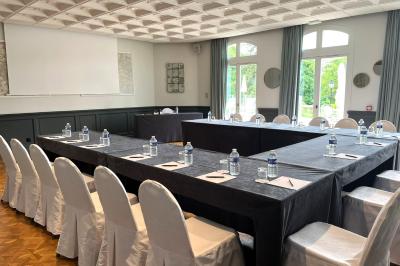 Chambre d'hôtel lumineuse avec lit double, coussins rouges, bureau, télévision et fenêtre donnant sur un balcon fleuri.