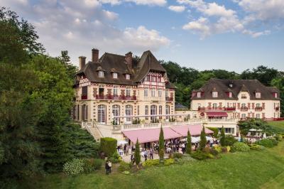 Chambre d'hôtel lumineuse avec lit double, coussins rouges, bureau, télévision et fenêtre donnant sur un balcon fleuri.