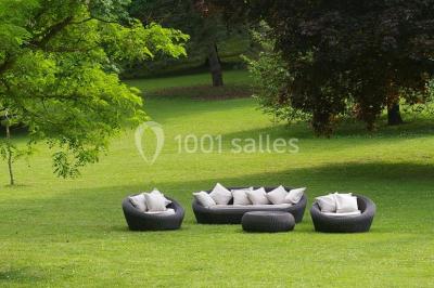 Chambre d'hôtel lumineuse avec lit double, coussins rouges, bureau, télévision et fenêtre donnant sur un balcon fleuri.