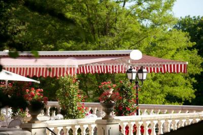 Chambre d'hôtel lumineuse avec lit double, coussins rouges, bureau, télévision et fenêtre donnant sur un balcon fleuri.