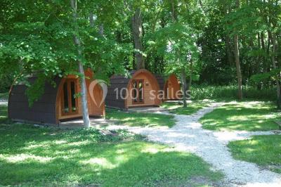 Rangée de cabines de toilettes avec portes en bois foncé, dans un espace carrelé et bien éclairé.