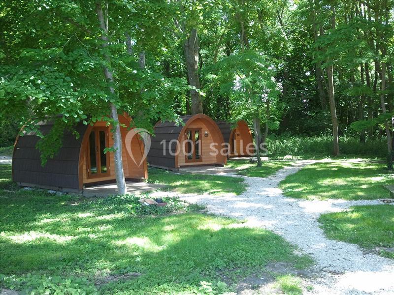Trois cabanes en bois en forme d'arc situées dans une clairière entourée d'arbres.