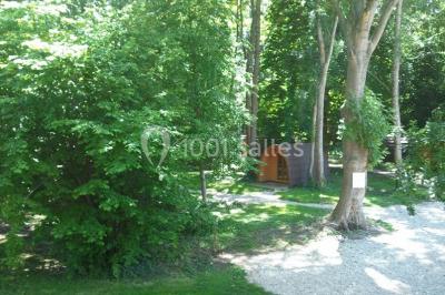 Rangée de cabines de toilettes avec portes en bois foncé, dans un espace carrelé et bien éclairé.
