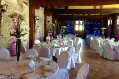 Chambre avec lit double, armoire en bois, canapé et tapis, murs en pierre et plafond avec poutres apparentes.