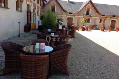 Chambre avec lit double, armoire en bois, canapé et tapis, murs en pierre et plafond avec poutres apparentes.