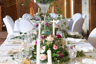 Chambre avec lit double, armoire en bois, canapé et tapis, murs en pierre et plafond avec poutres apparentes.