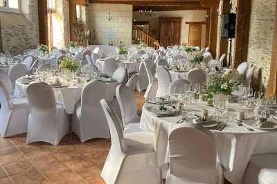 Chambre avec lit double, armoire en bois, canapé et tapis, murs en pierre et plafond avec poutres apparentes.